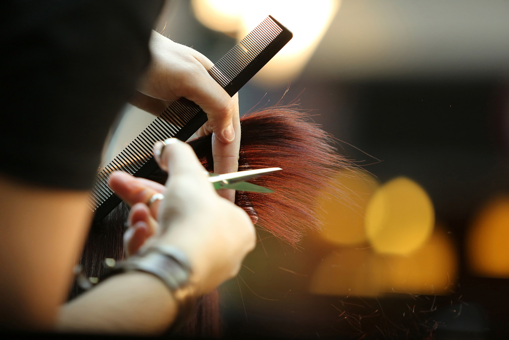 scissors cutting ends of red hair