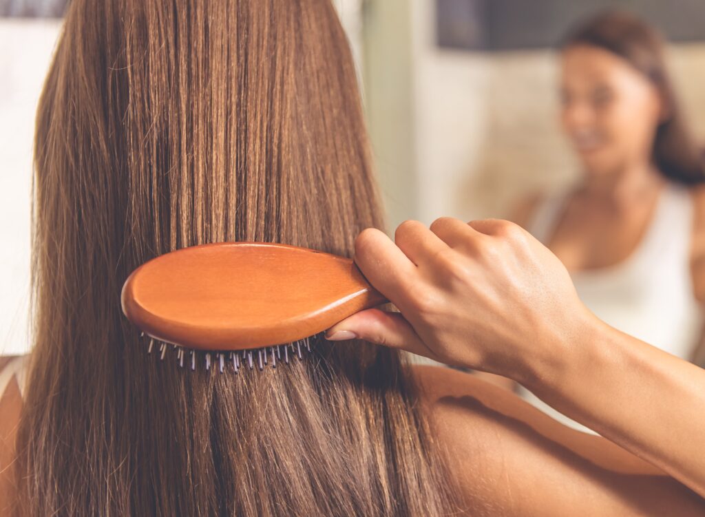 back view of woman brushing her hair in the mirror