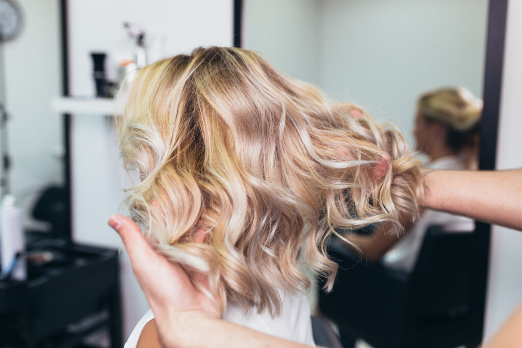 blonde woman with shiny curls at the hair salon
