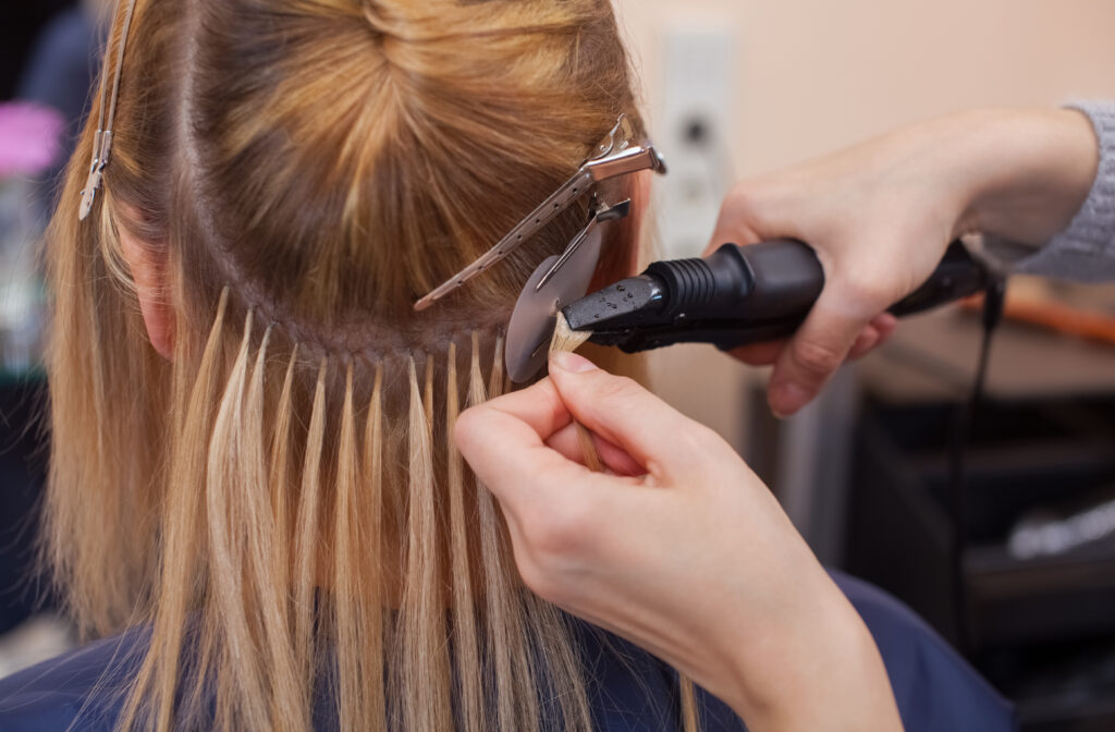 woman getting hair extensions installed on head