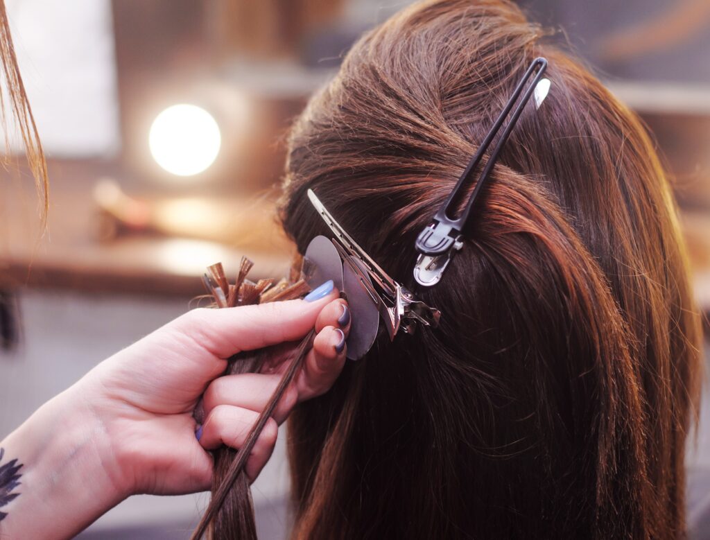 dark haired woman having hair extensions installed