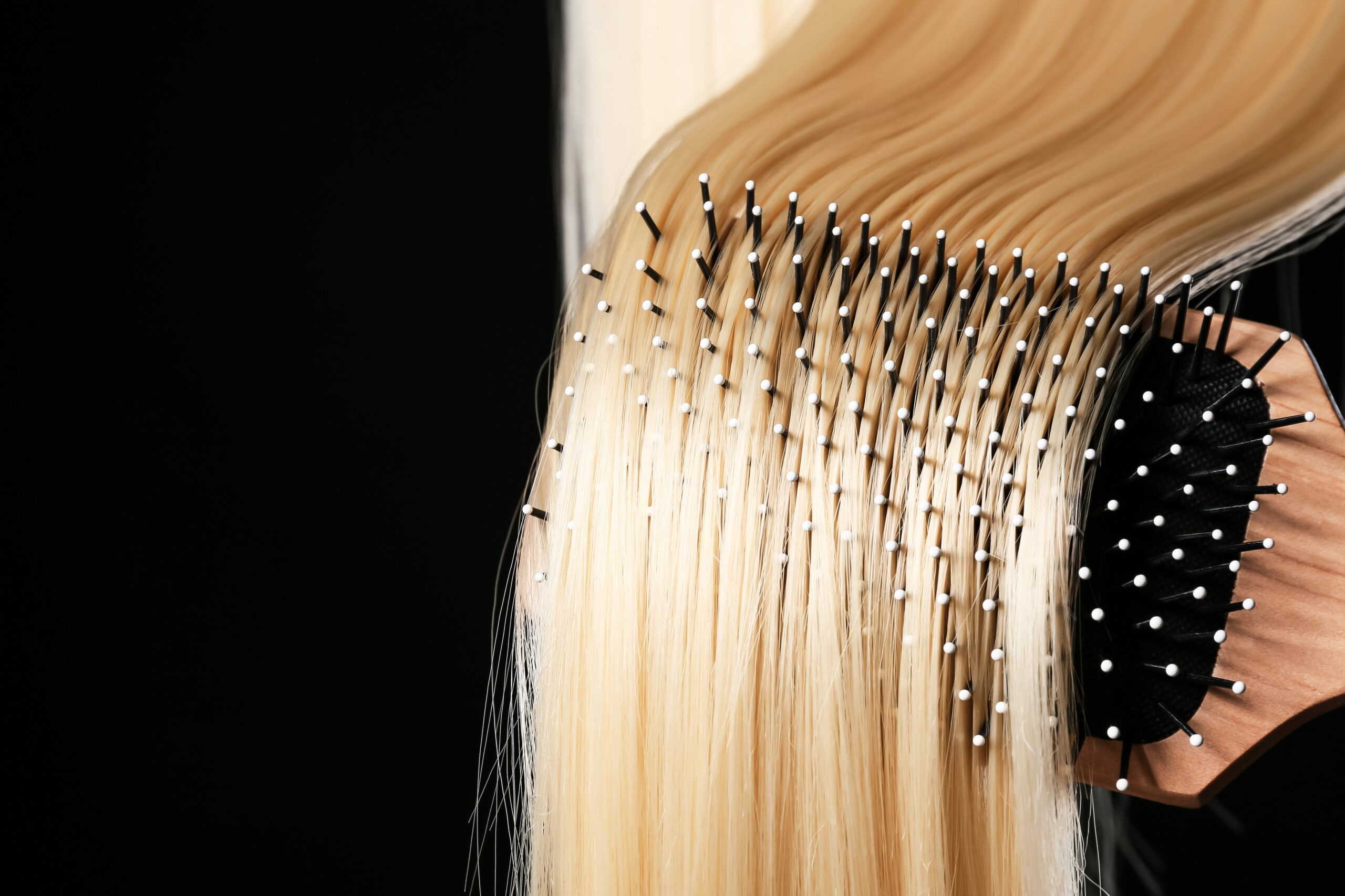 close up of brushing blonde hair extensions