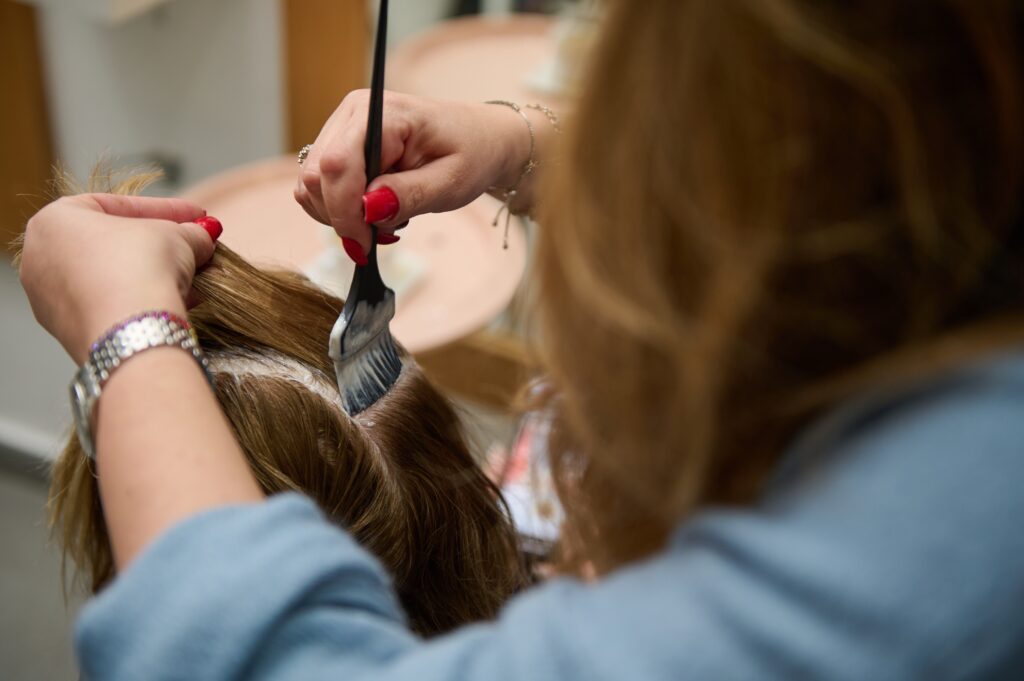 stylist brushing hair dye on women clients hair