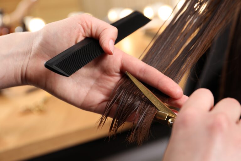 hair dresser cutting the ends of woman's hair at hair salon