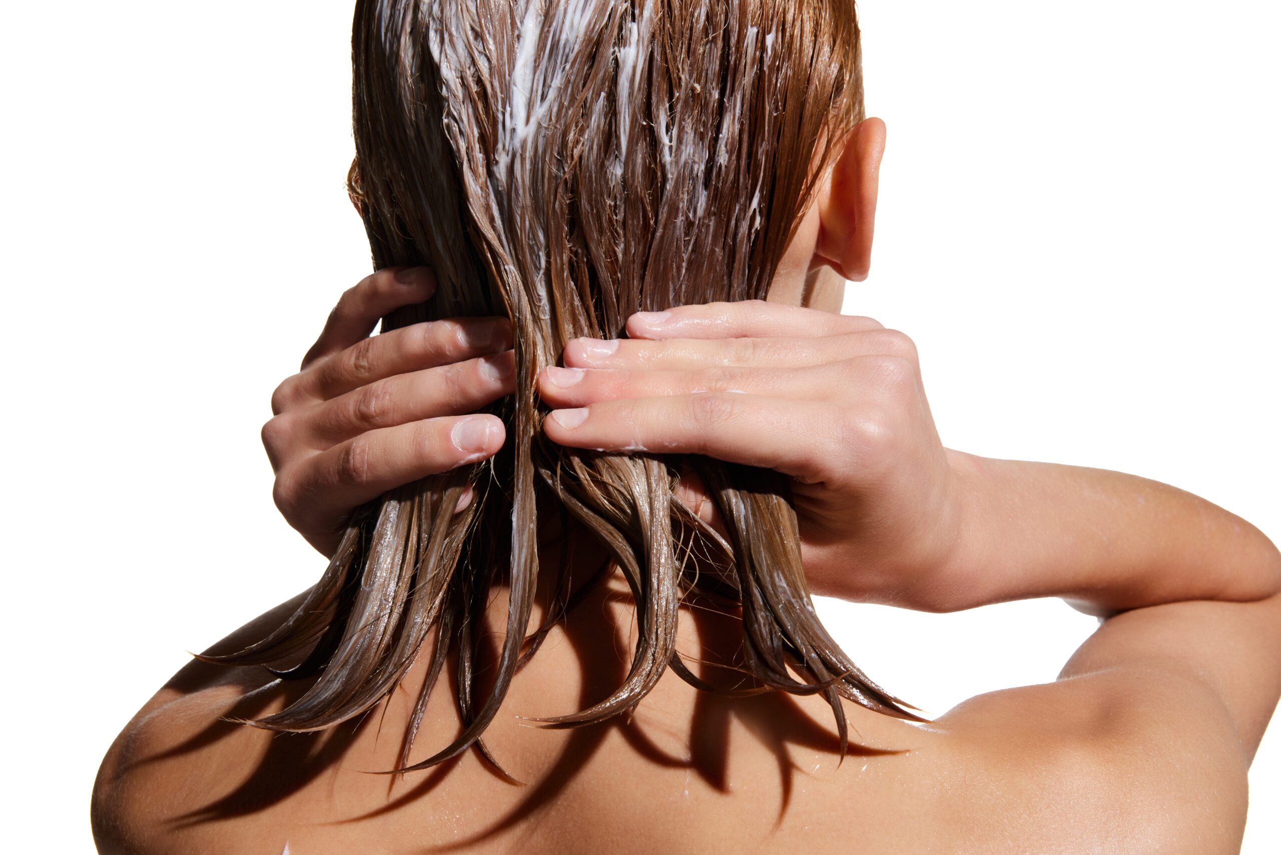 back of a woman using a hair treatment on her hair in the shower