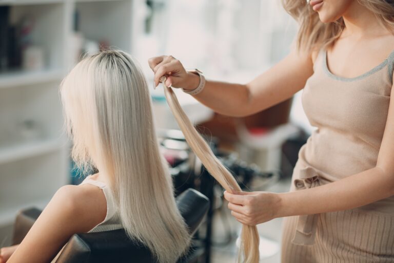 hair extensions being inserted in the salon on a client with blonde hair